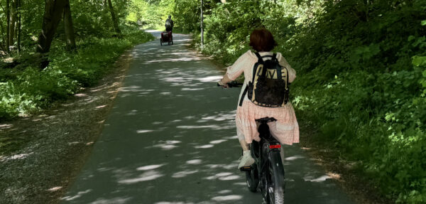 Zwei Radfahrer fahren von der Kamera weg auf dem Radweg im Friedenstal